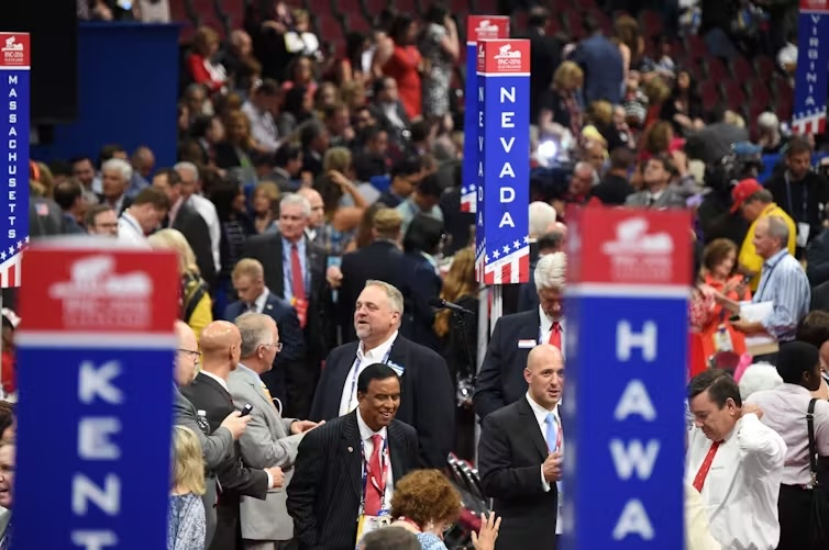 Click to view larger image A crowd of people with tall pillars in red, white and blue with state names on them.