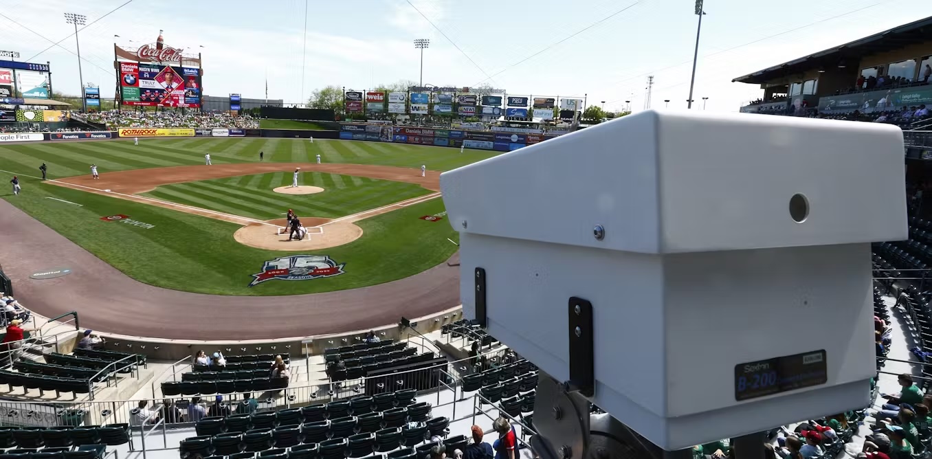 Click to view larger image A white camera installed in a baseball stadium overlooking the field.