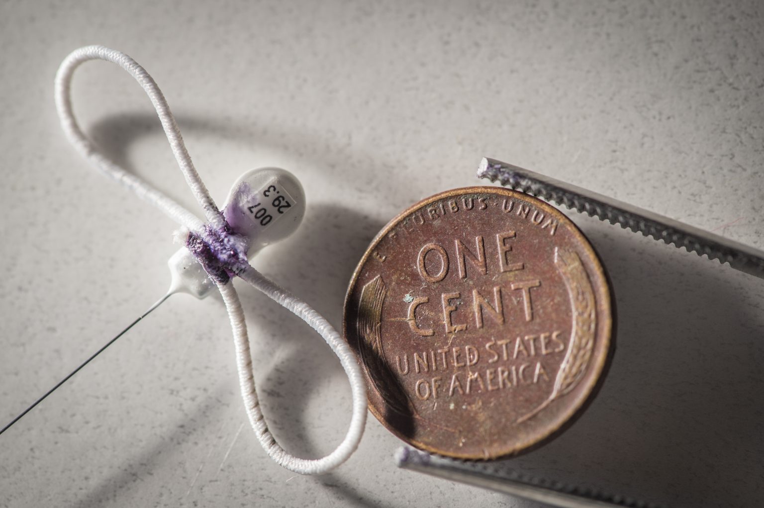 A small GPS device sits next to a penny to show relative size.