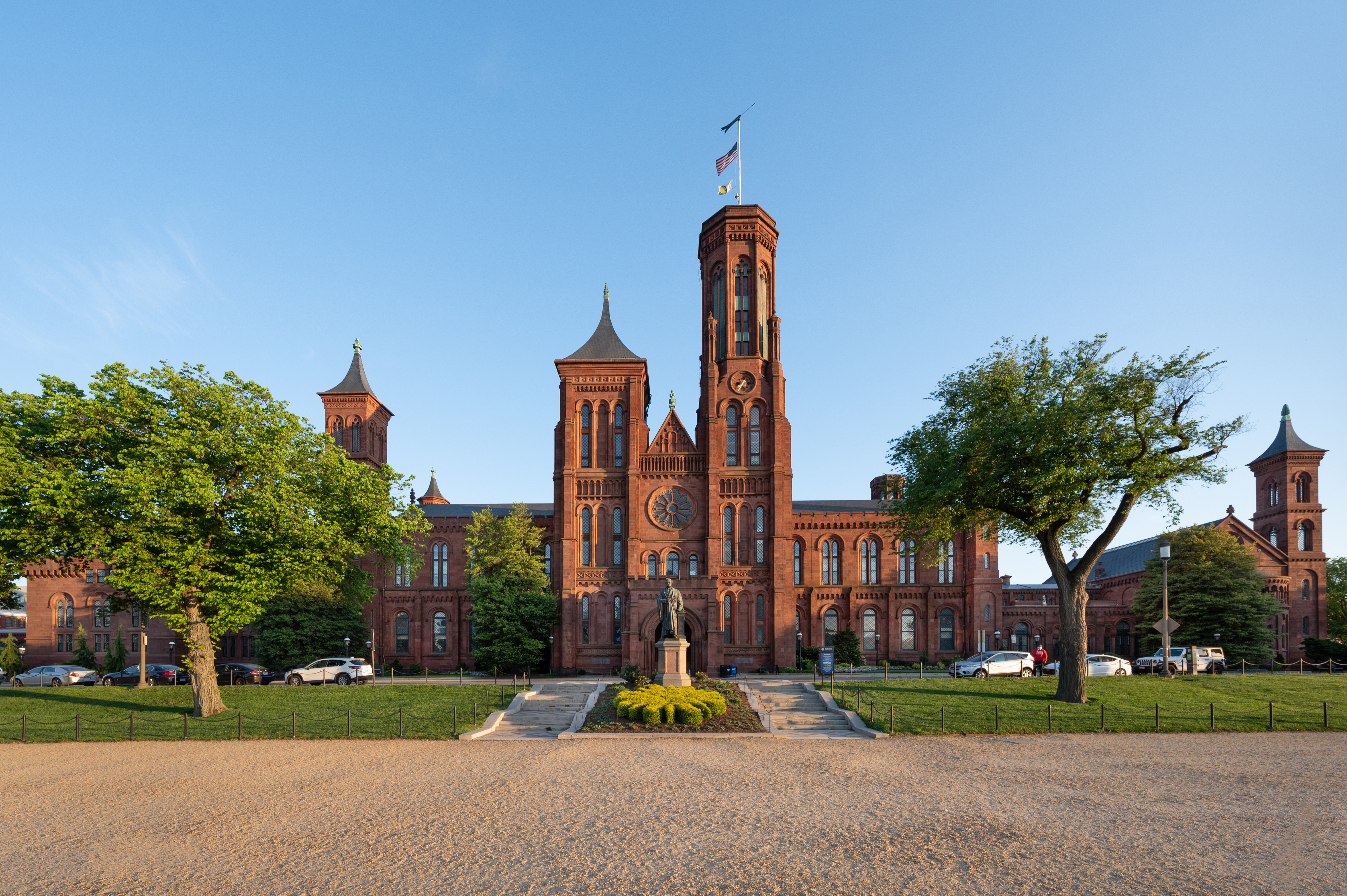 Red brick building with a spire and green landscaping.