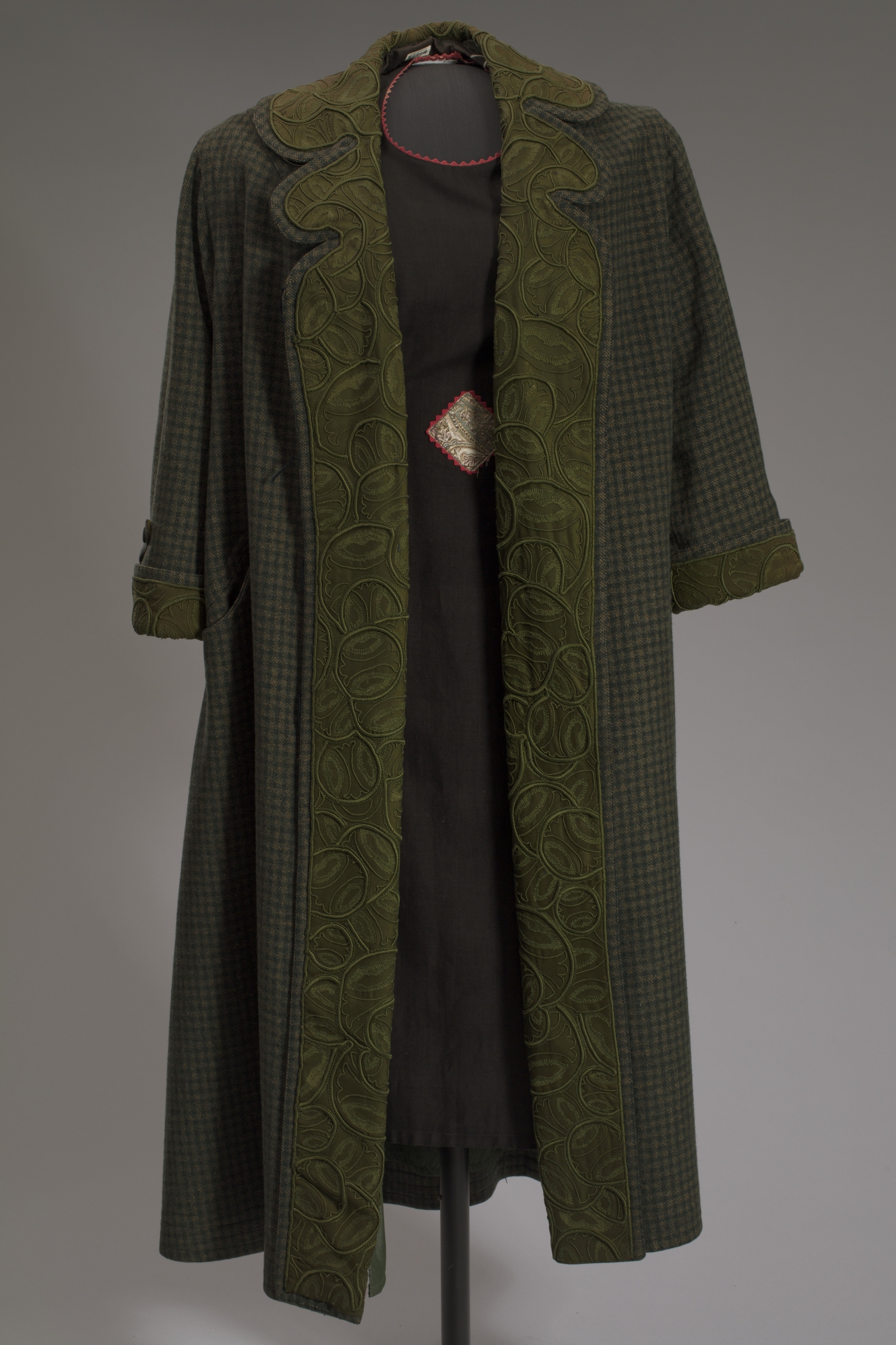 Long green jacket with detail around border.
