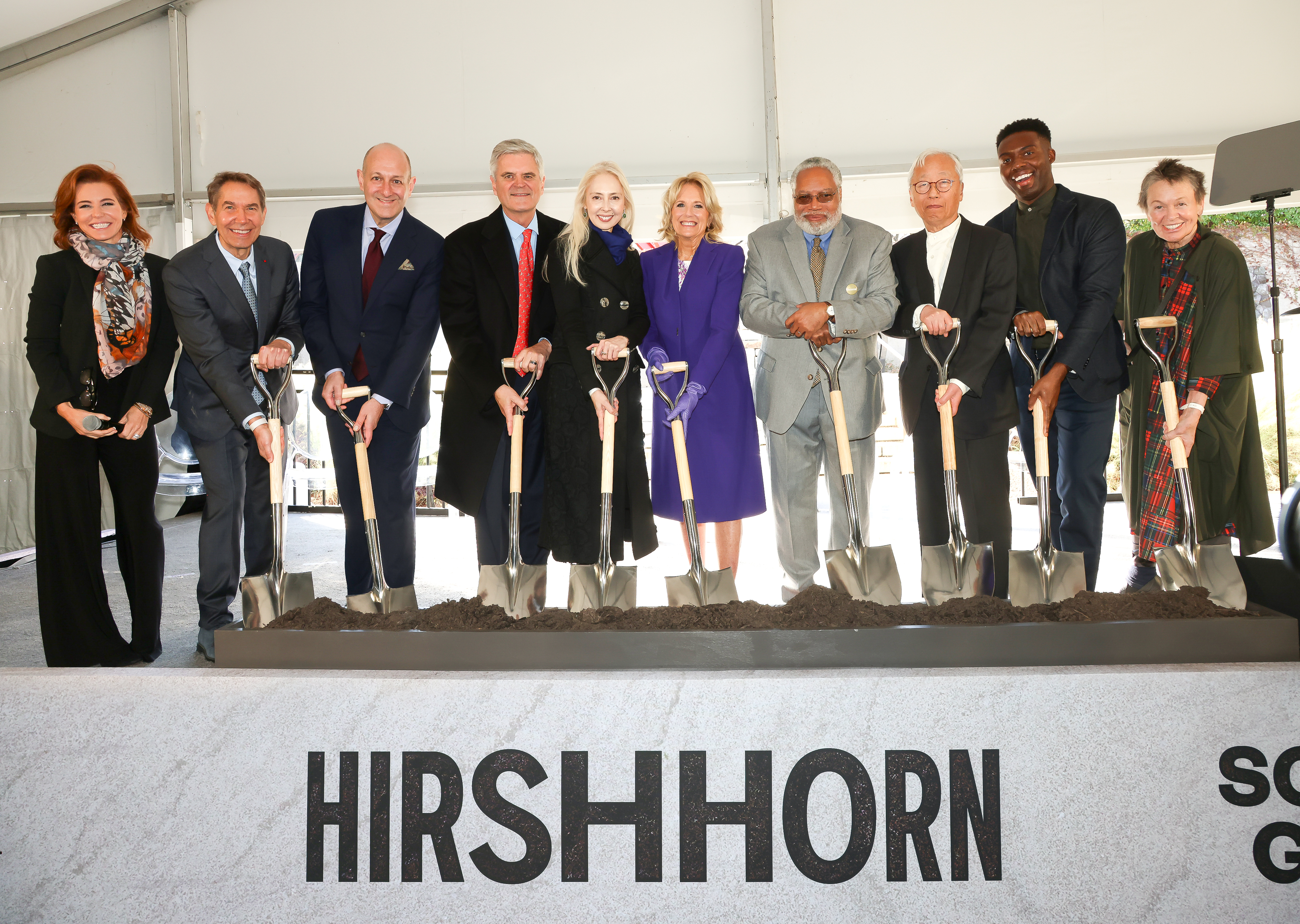 Group of people each pose with shovels in their hands, smiling ahead