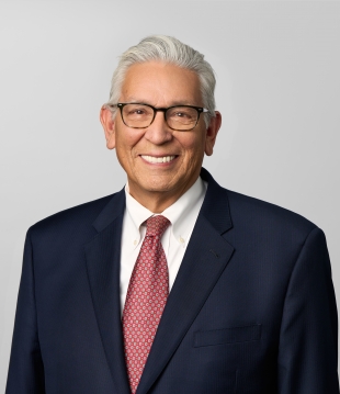 Man in a dark suit and red tie, wearing glasses, smiles for a headshot.