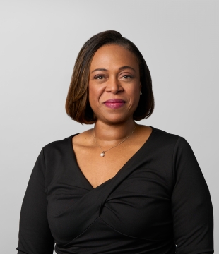 Woman with chin-length black hair and a black v-neck top smiles toward camera.