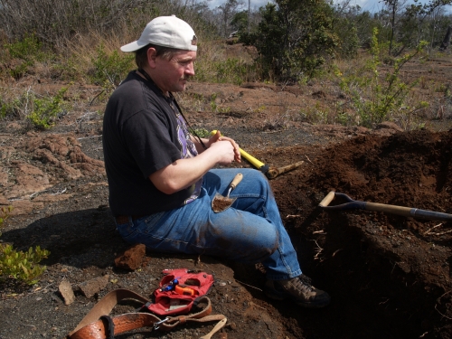 Tim Rose sits on the edge of a large hole in the ground.