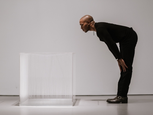 Man leaning over to look at a clear cube