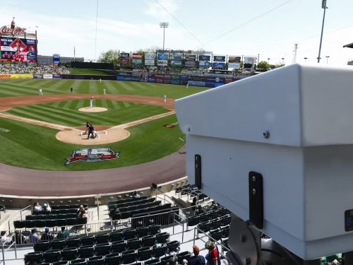 A white camera installed in a baseball stadium overlooking the field.