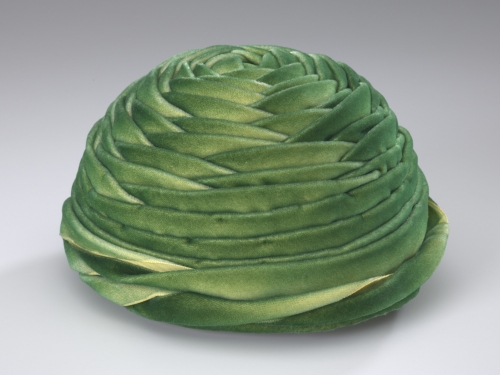 Green velveteen hat. It is circular with layers of fabric in a wrapped design.