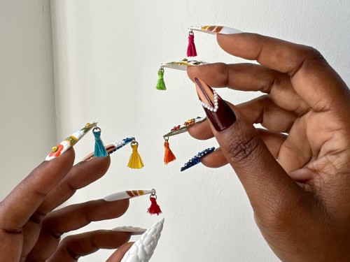 A close-up of a person's hands displaying nails featuring a variety of colorful and artistic designs.