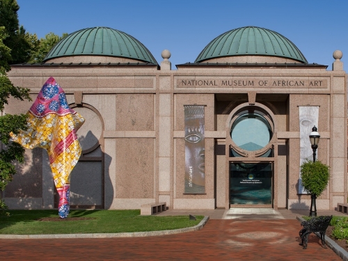 Facade of building with colorful sculpture and large doorway.