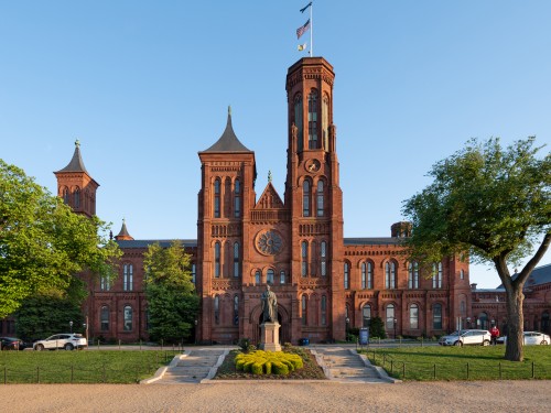 Red brick building with a spire and green landscaping.