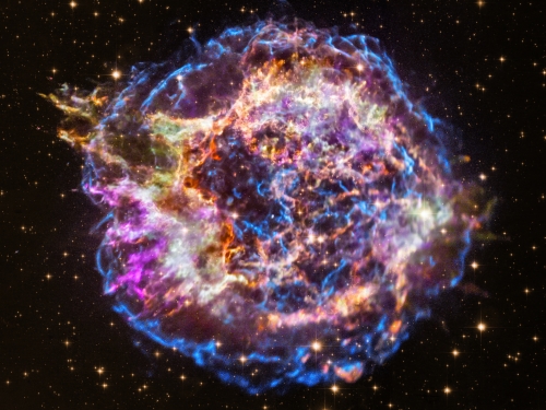 Image of a nebula in outer space, with a circular blue rim and interior colors of bright pink, orange, and white.