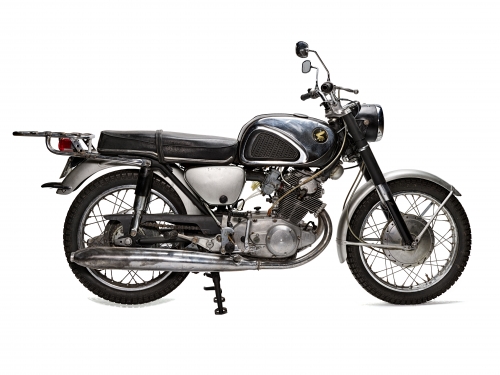 Side view of black and silver motorcycle, with kickstand down, against white background.