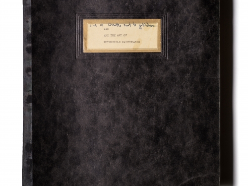 Black, soft-covered book with tan, hand-written label on the cover.