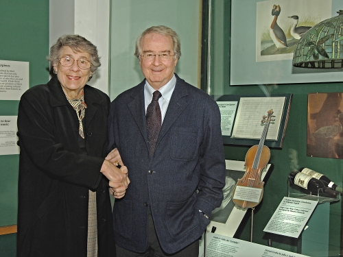 Two people shaking hands in front of a museum exhibit case