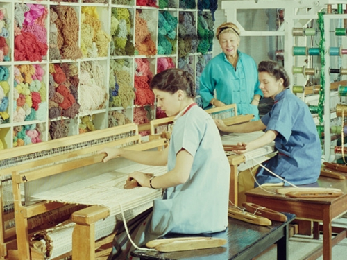 Two women work in front of a textile loom