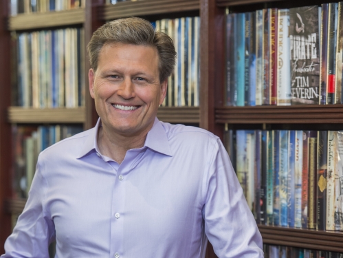 David Baldacci leans against bookcase