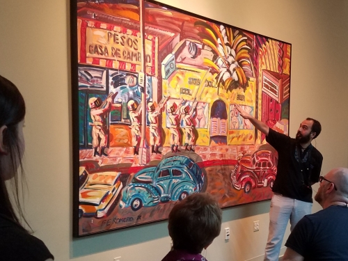 Docent explaining large colorful painting to onlookers