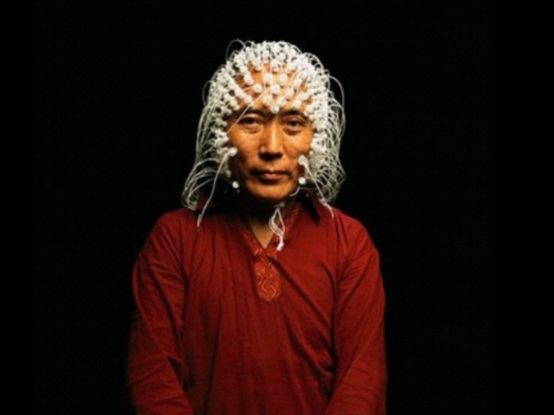 Person in red clothing and headdress stares forward