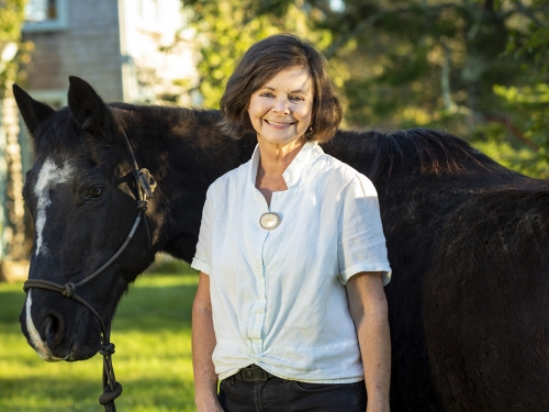Woman stands next to horse