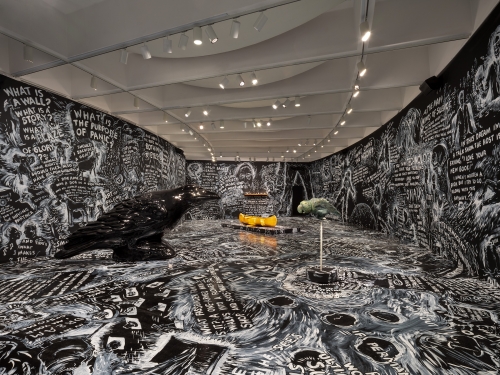 Museum gallery with curved walls painted black and white writing and drawings all over the.