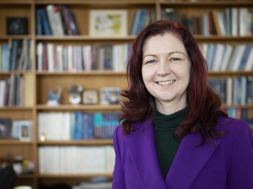 Woman smiles in front of bookcase