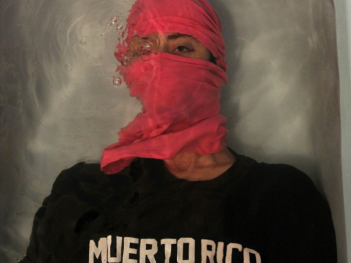 Portrait of man in red head scarf and black shirt saying Muerto Rico