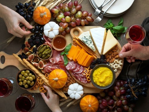 two hands select cheese from platter of holiday food