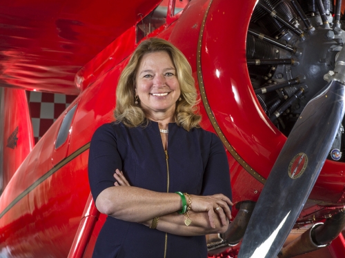 Ellen Stofan smiles with her arms crossed in front of an airplane