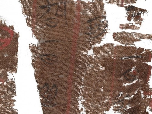 Torn pieces of brown cloth with faded black calligraphy.