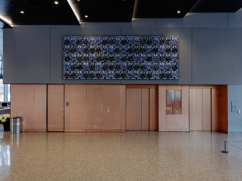 Black and blue patterned painting hangs above doorways and elevators in museum lobby.