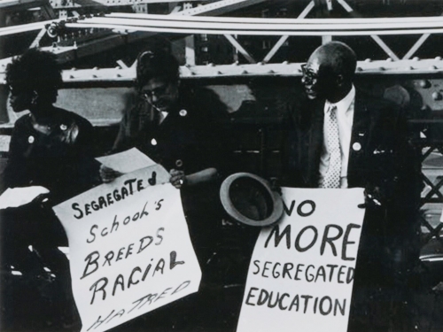 Black and white image of three people sitting with protest signs.