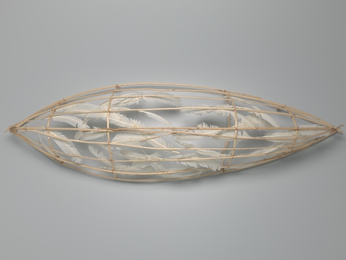Sculpture in pointed oval shape made out of light wood and white feathers.