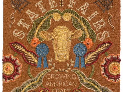 Textile in warm colors with floral designs, a cows face and lettering.