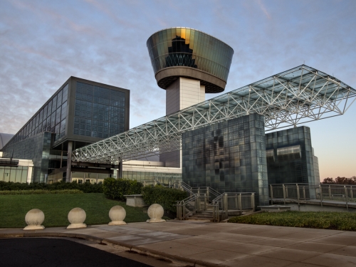 Exterior of building with large overhang over entrance and glass airplane tower,