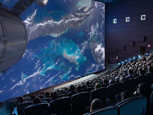 An audience sits while watching an imax film.