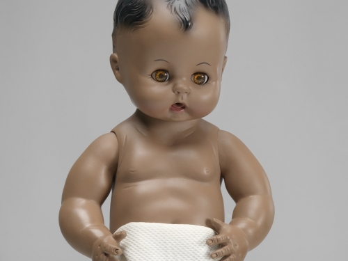 An African American baby doll. The doll has open- and close- eye functionality and wears a cloth diaper.