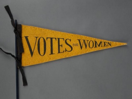 A yellow pendant that says votes for women.