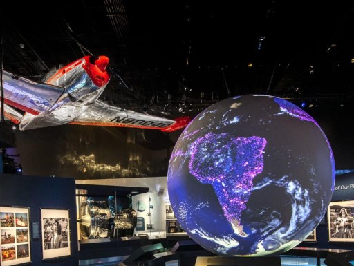 A photograph of the exhibition, featuring an airplane in flight and a illuminated planet.