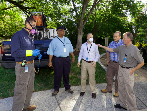 image of a group of men one wearing a mask with a respirator on it and a man pointing