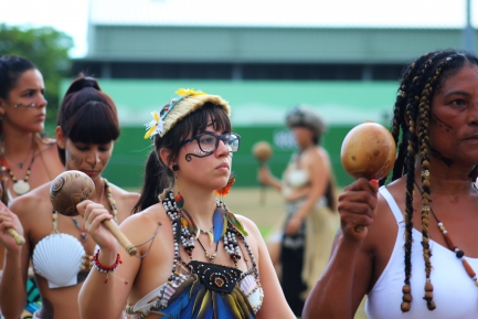 Girl in native dress with face painting shaking gourd rattles