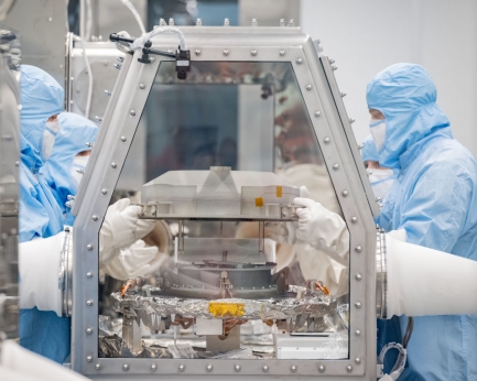Technicians working with asteroid sample in clean room