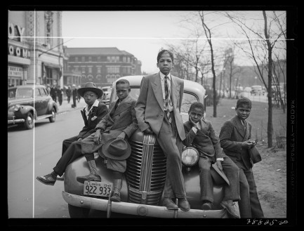 Dressed up Black boys sitting on hood of car
