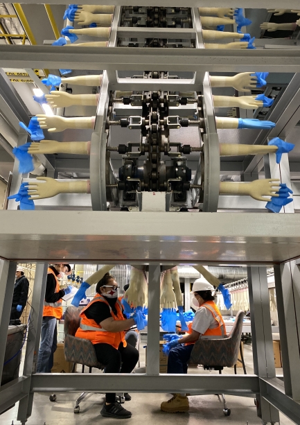 Two people sit while working in a factory setting.