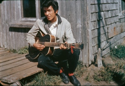 Vintage photo of a man playing a guitar on a porch
