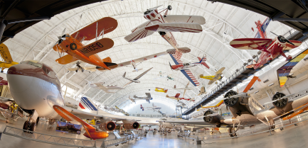 Panorama of indoor hangar with planes of various sizes and colors