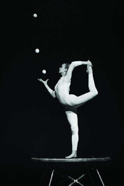 Black and white photo of woman in yog pose juggling