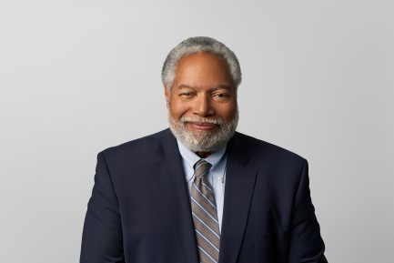 Man wearing a suit and tie smiles for a professional headshot.