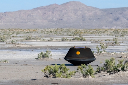 Black capsule sits in desert.