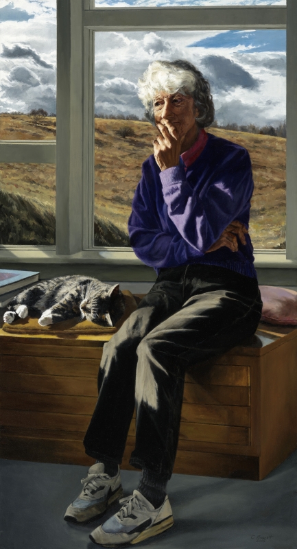 Woman with white bob and purple sweatshirt sits, crossing her arms, in front of a window overlooking an open field.